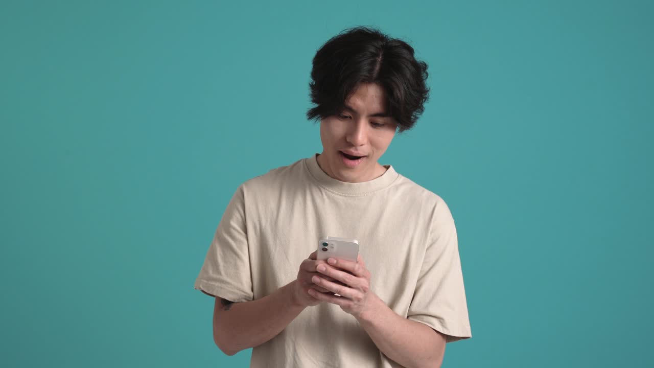 Happy Asian man typing by phone