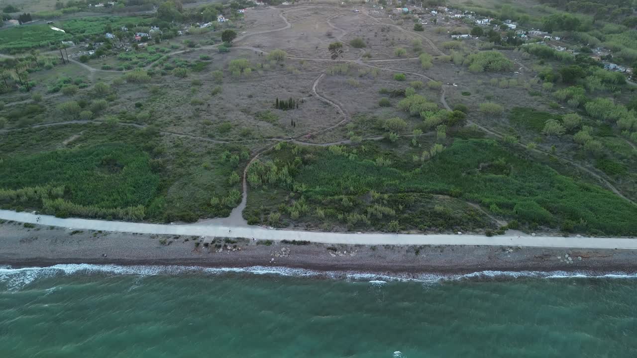 해가 지는 동안 스페인의 지중해 해변을 위에서 아래로 보는 드론, 해변 길을 따라 고 운동하는 사람들과 함께
