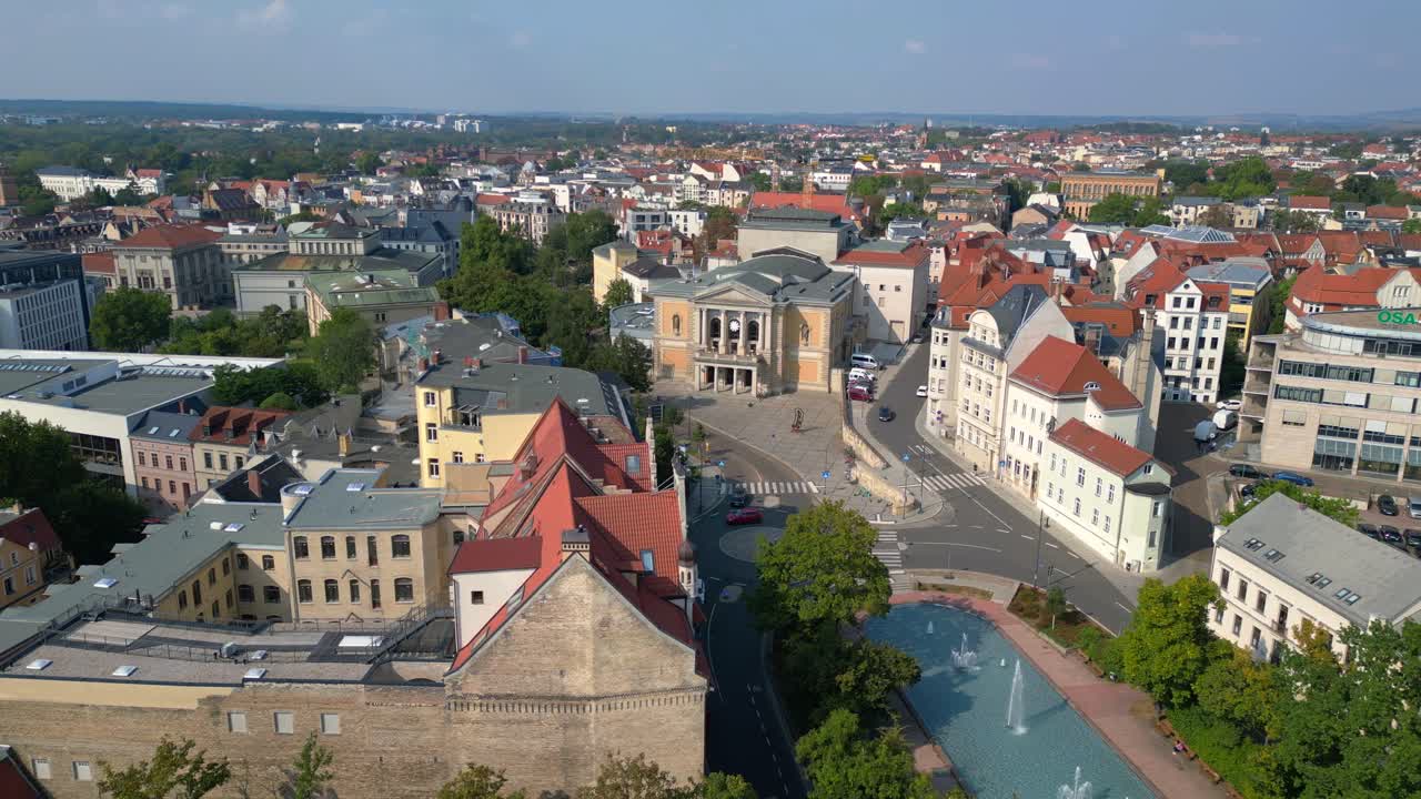 Fountains are cascading in front of the opera house on a sunny day in halle saale, germany. drone shot footage from above