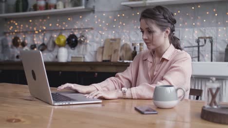 mujer trabajando desde casa en una computadora portátil en una cocina