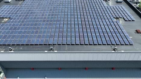 aerial pullback across large industrial roof with organized column rows of solar panels