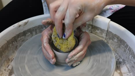 young woman artist making clay bowl on pottery wheel