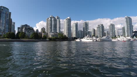 aerial fly over false creek with waves caused by motor boats pass by at an aquatic marina where yachts are parked in false creek yaletown next to the david lam park by the modern condominiums sunny3-3