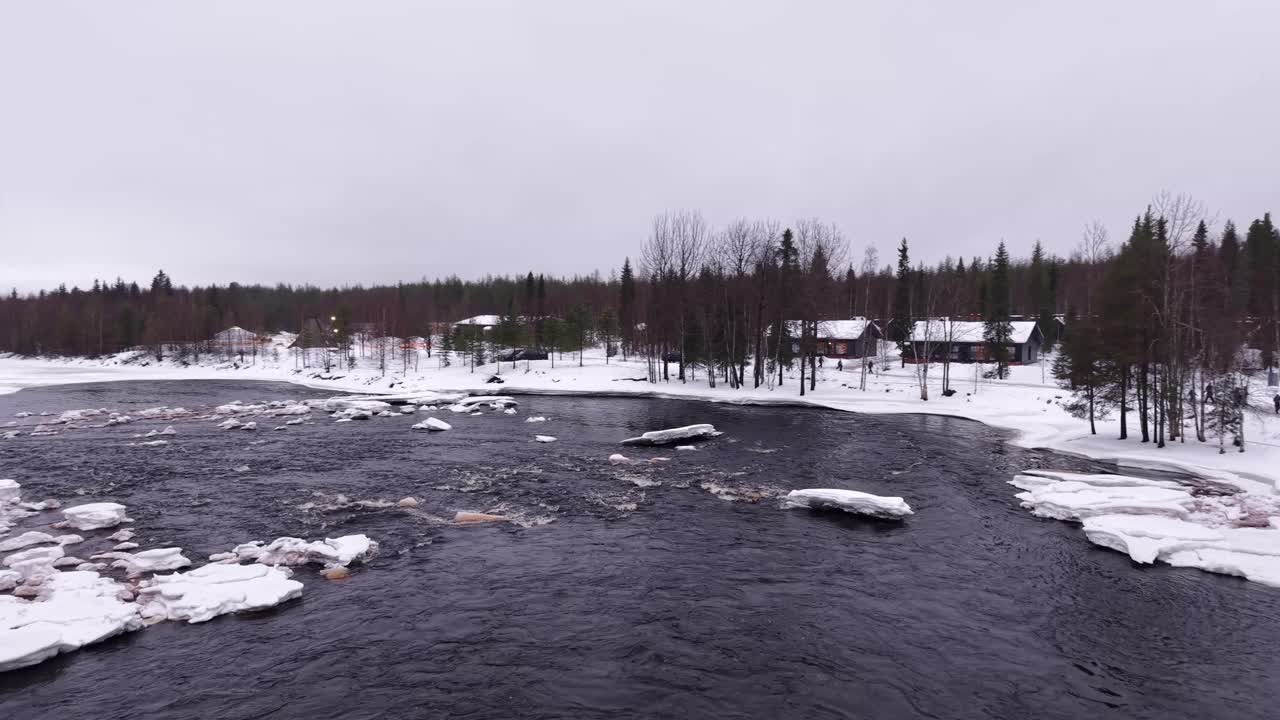 Lapin punertavanruskea joki lumipeitteisellä rannalla, Joulupukin kylä, Suomi, ilmakuva