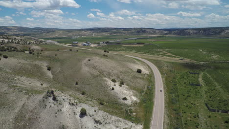 drone view of lone car driving down an empty road in the midwestern us