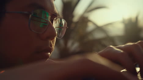 man coding outdoors with data reflected on glasses