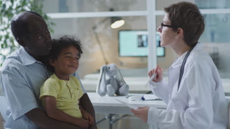 doctor examining a child with his father