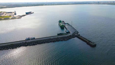 aerial drone video orbiting at a high altitude over a pier or a dock at a harbor during a sunny day with metal industrial cargo and trading ships attached to it at paljassaare peninsula at summer