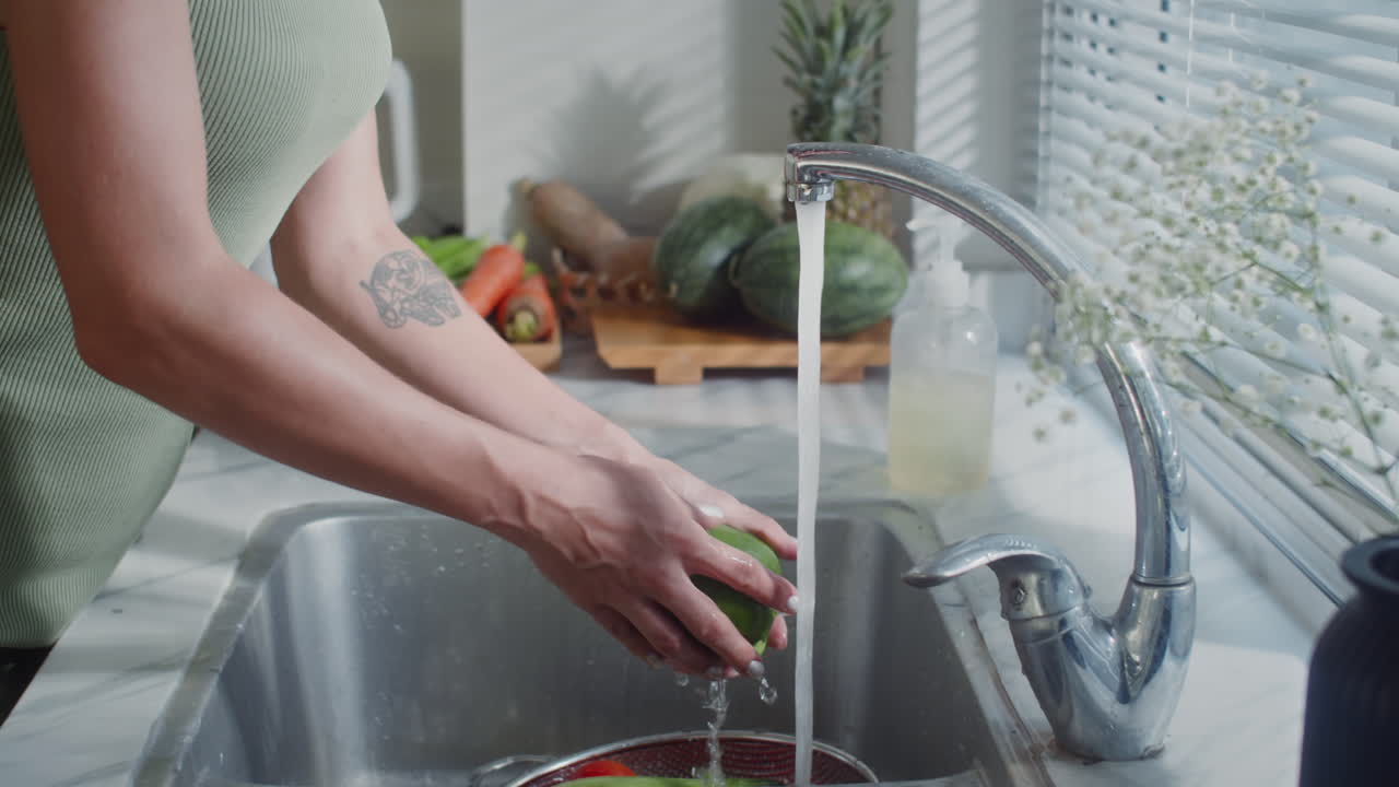 Woman Washing Vegetables at Kitchen Sink