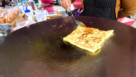 preparing roti or similar flatbread on a street food stall