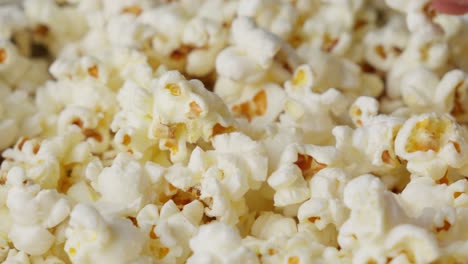 close up of hand grabbing taking popcorn snack from the pile