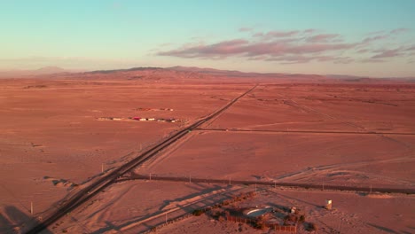vista aérea de una calle única en el desierto del norte de chile con las áridas montañas en el fondo, puesta de sol, región de coquimbo
