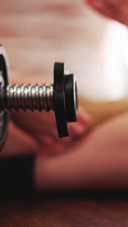 playful little boy removes gear from heavy barbell with hand. cute toddler sits on floor in gym playing with professional equipment closeup slow motion