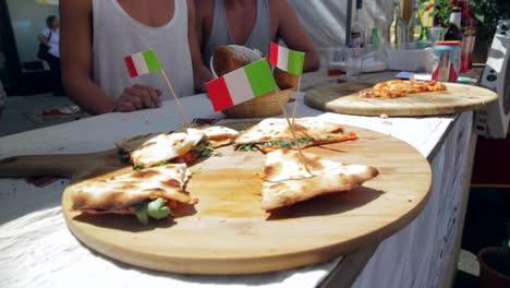 pizza on a wooden board at street food market with italian flags