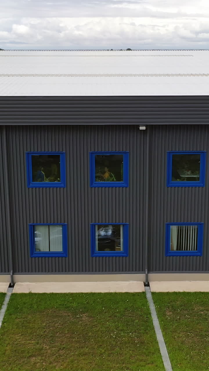 Modern two-storey building. Exterior of a new industrial building. View from outside on a business center in summer time. Vertical video