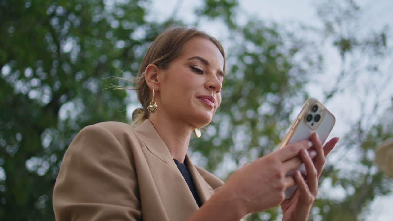 Primo piano di una ragazza al parco che messaggia al cellulare. Donna d'affari attraente che digita sul dispositivo.