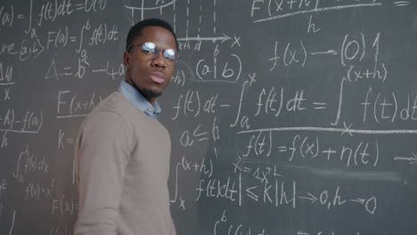 man writing equations on a chalkboard