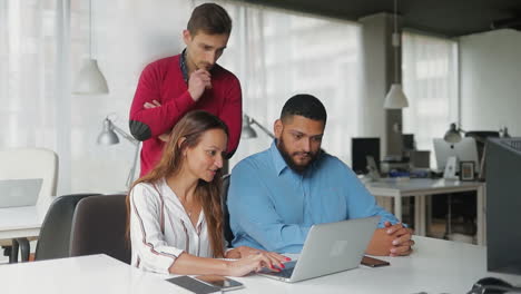 Cheerful-business-team-working-with-laptop--in-modern-office.