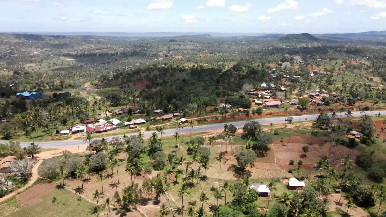 vista circular de un avión no tripulado sobre un pequeño pueblo y palmeras al lado de la carretera de mombasa