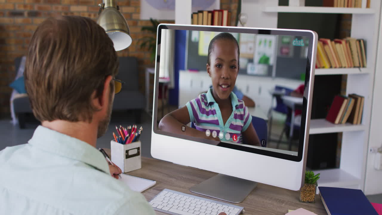 Caucasian male teacher having a video call with school girl on computer at school