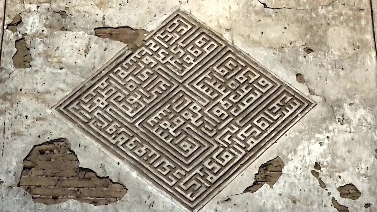 Intricata calligrafia islamica geometrica intagliata in un'antica parete di pietra