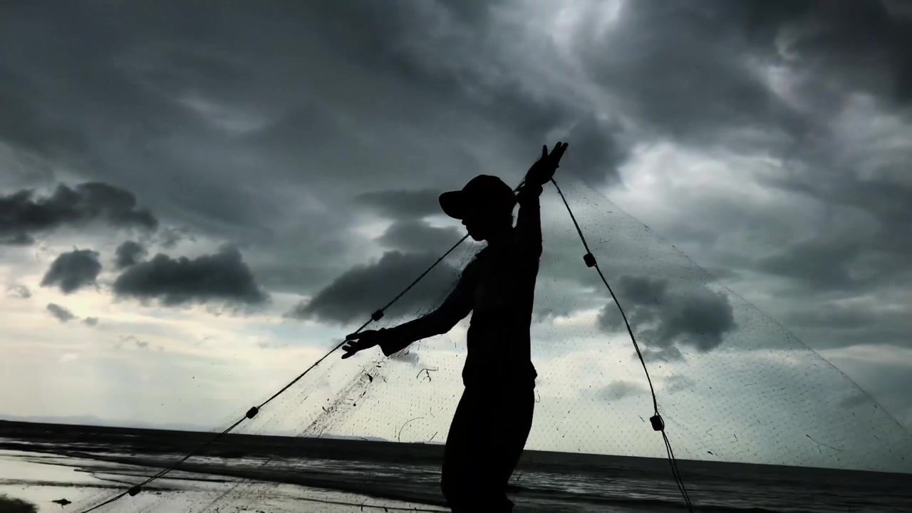 Video cinematografico in 4K ad alta definizione di un pescatore che rimuove il pescato da una rete dopo una raccolta di successo in mare.