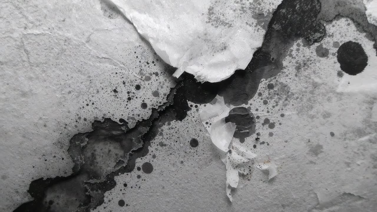 Zooming camera revealing torn white layer peeling on textured wall at close-up, with dark stain
