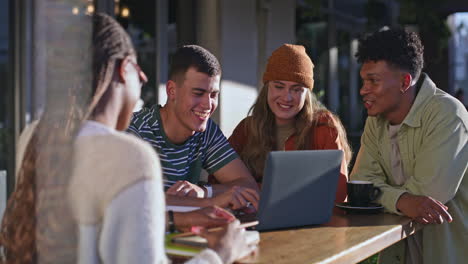 group of friends working together on a laptop at an outdoor cafe