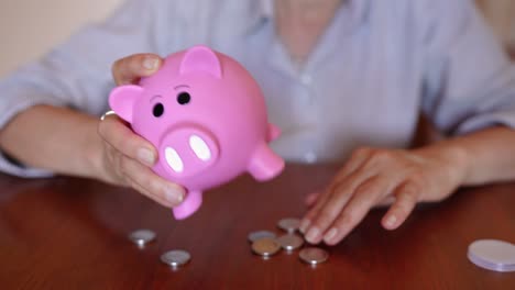 mujer quitar el tapón extraíble en la parte inferior de la alcancía para sacar las monedas
