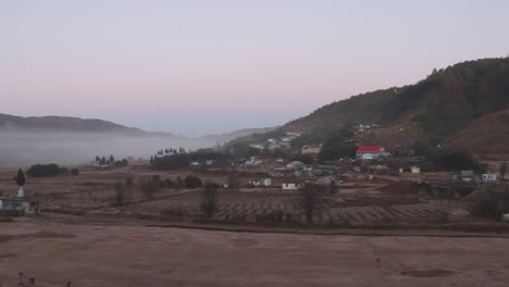 pequeño pueblo remoto en las faldas de las montañas con niebla y cielo plano por la mañana desde un ángulo plano