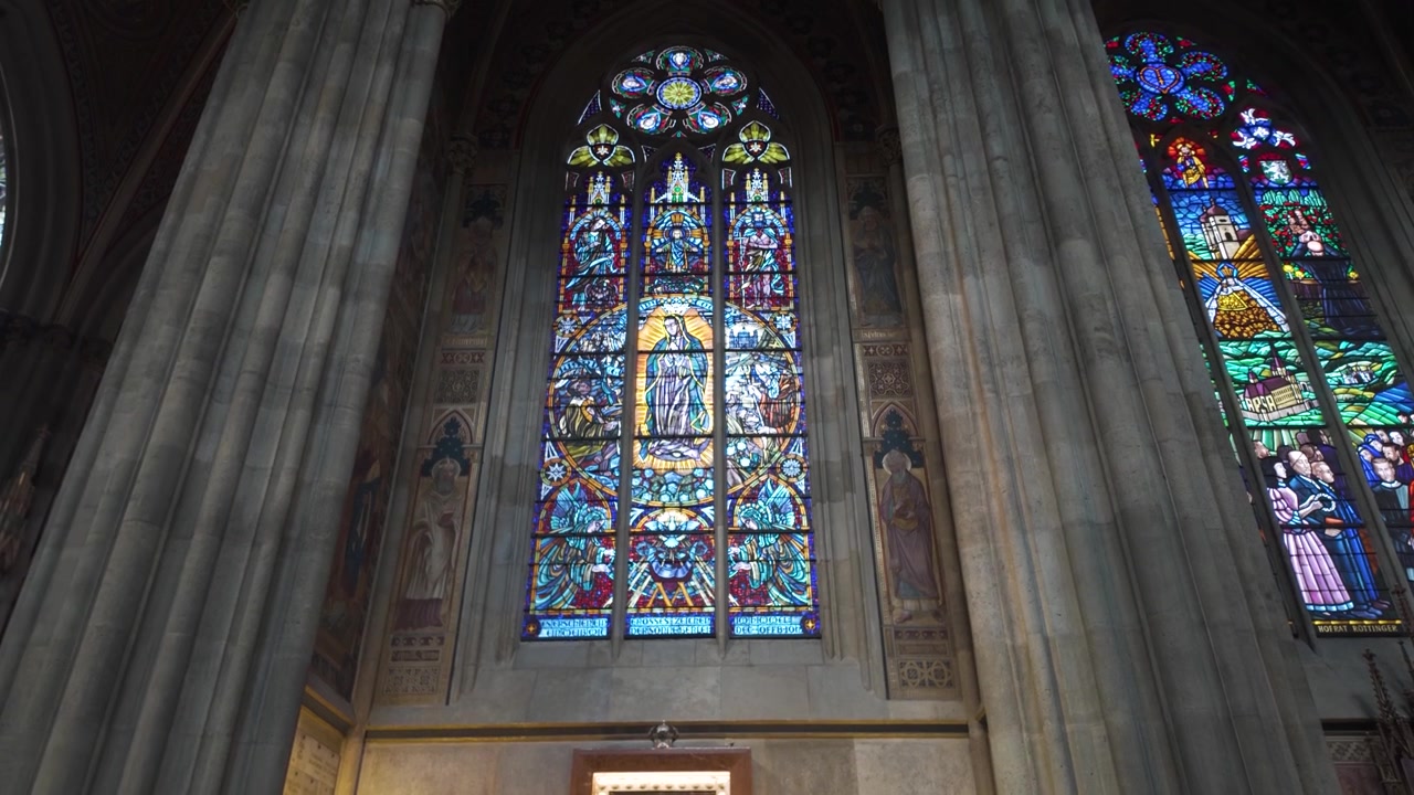 Vista interna della Chiesa Votiva a Vienna, con vetrate colorate e icone religiose.