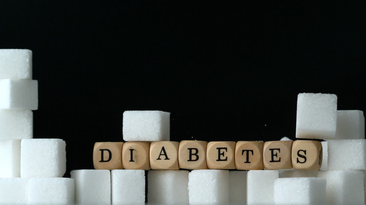 Terrones de azúcar y dados formando la palabra diabetes cayendo sobre fondo negro sobre una pared de terrones de azúcar