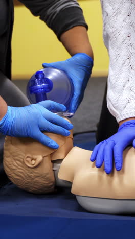 first aid reanimation. women in safety gloves trying resuscitation technique on dummy. cardiopulmonary training on a mannequin. healthcare and medical concept. vertical video