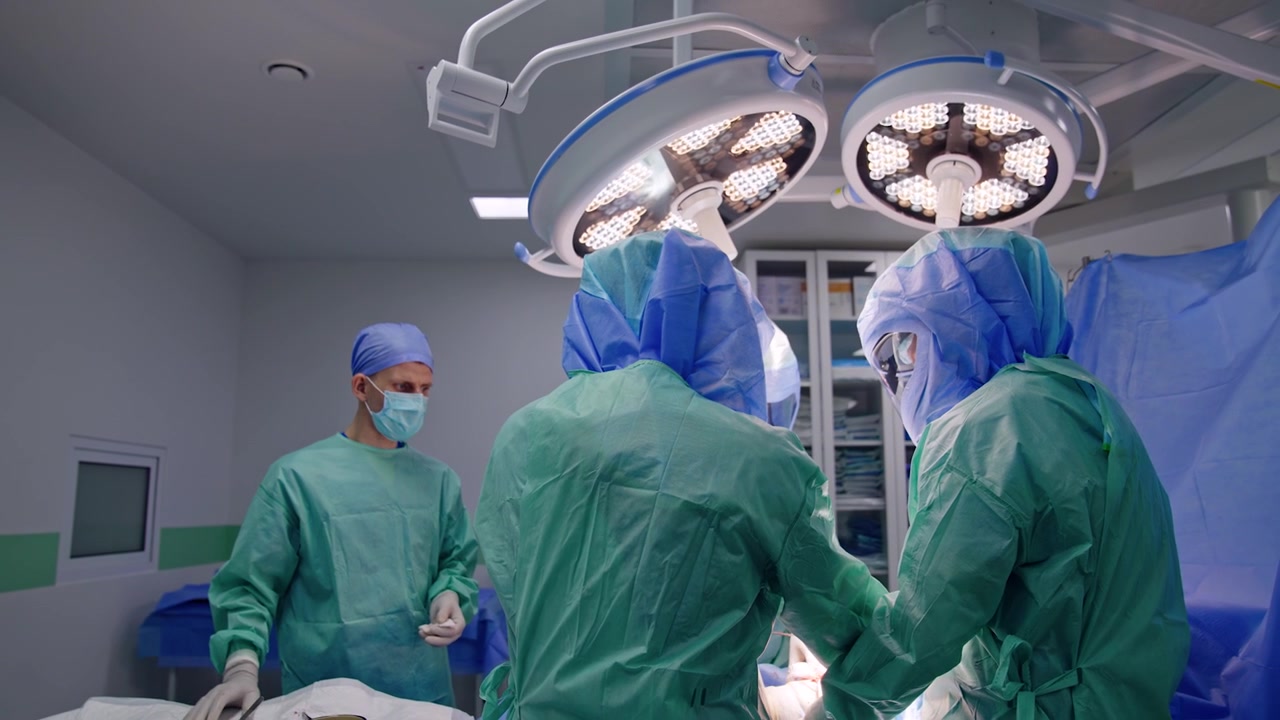 Tre chirurghi uomini e un assistente collaborano all'operazione in una moderna sala operatoria. Procedura ortopedica eseguita dal team professionale