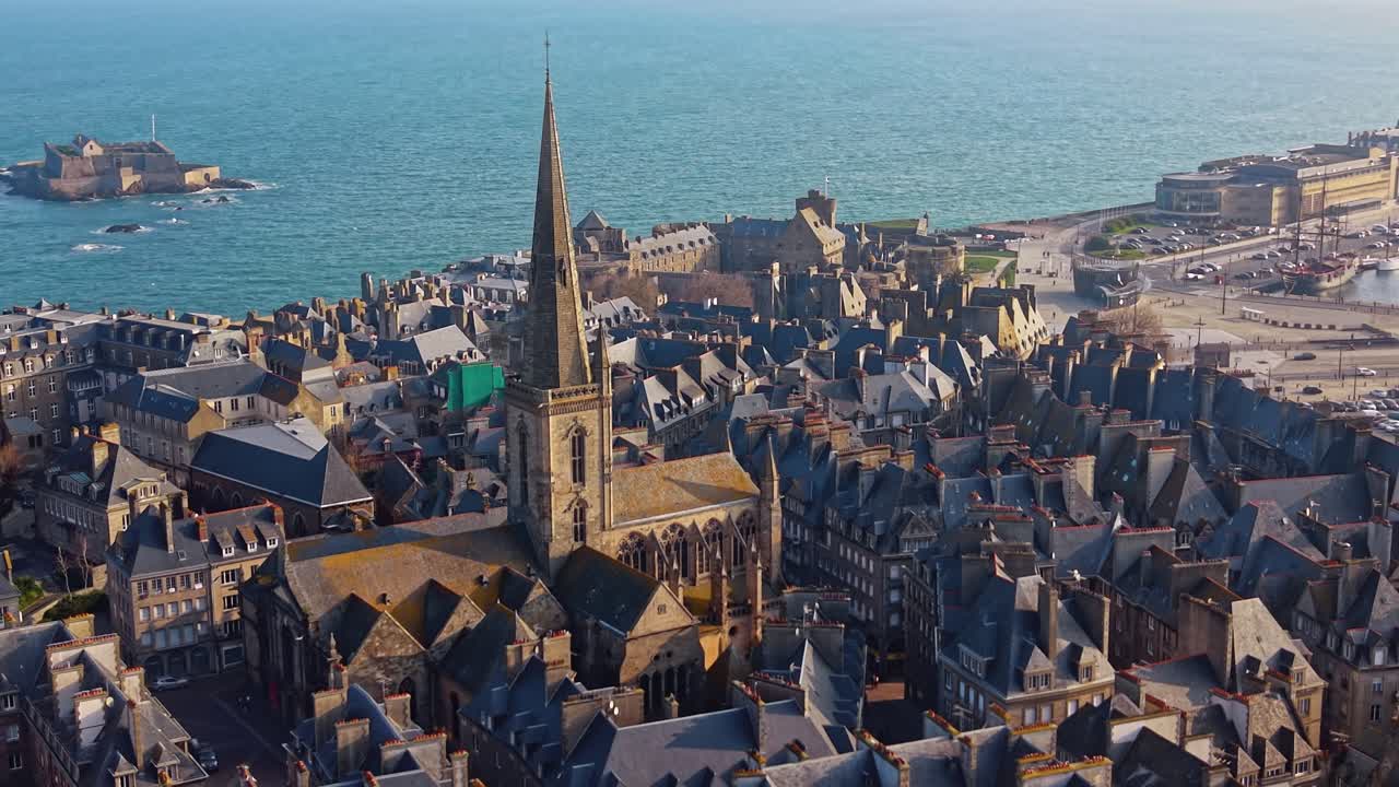 Drone bergerak melintasi Katedral Saint Vincent dengan laut, balai kota, dan benteng Nasional di latar belakang. Saint-Malo Intra-Muros, Brittany di Prancis