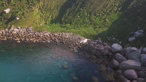 Aerial-side-view-of-broken-boat-on-rocks-in-Isla-del-Arvoredo,-Florianopolis,-Brazil