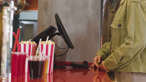 happy couple selecting movie from screen and buying tickets at cinema