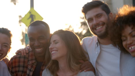 group of smiling young adult friends embracing in the street