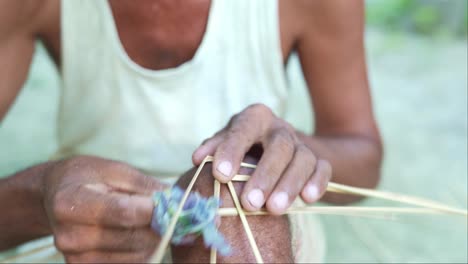 artesano indio artesano asiático de cerca haciendo un producto hecho a mano con un palo de bambú