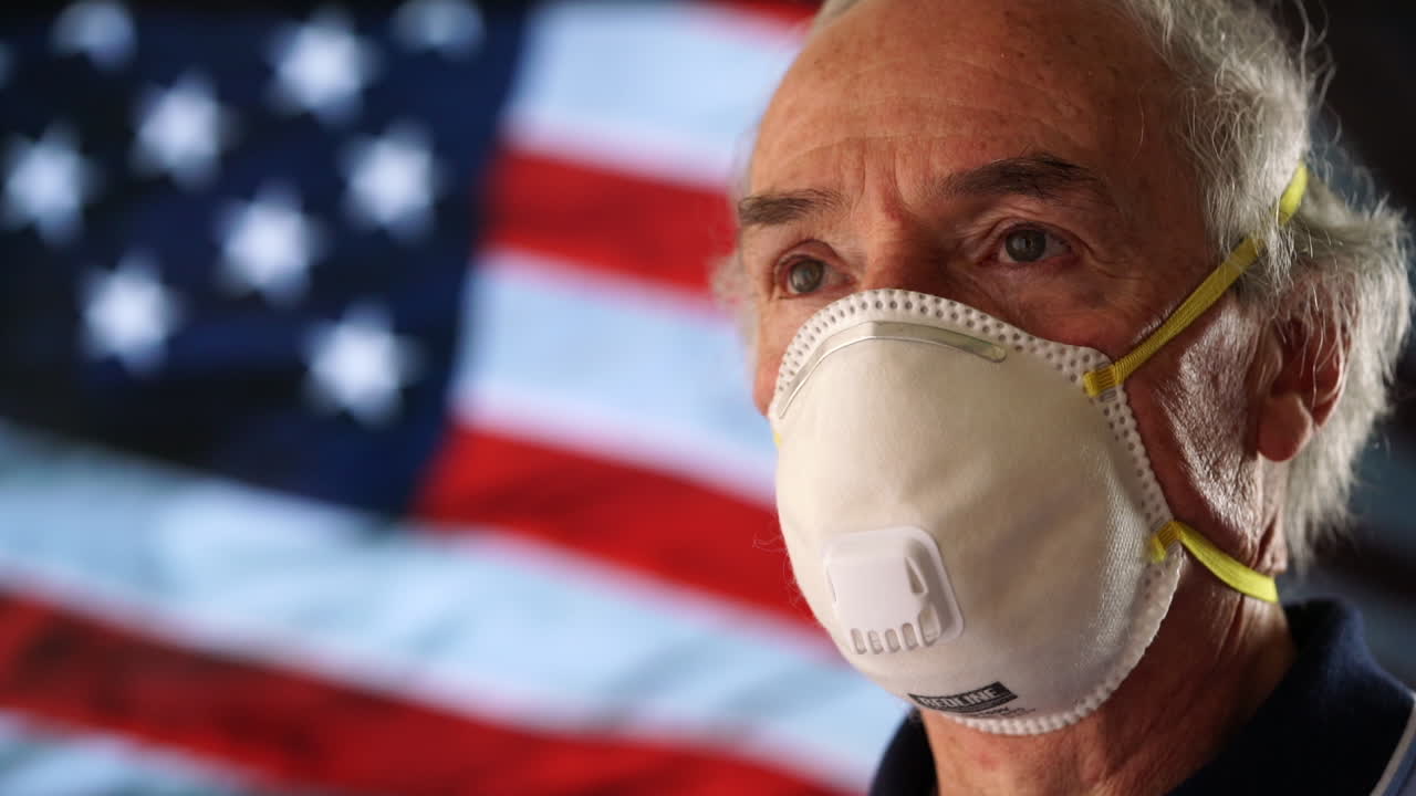 Elderly Man Wearing N95 Mask with American Flag in Background