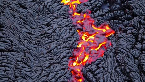 aerial view of vibrant lava flow on textured, dark volcanic rock