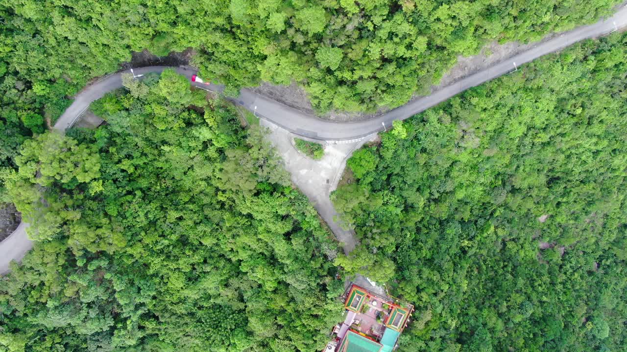 vista aérea de una estrecha y sinuosa carretera de montaña rodeada de una exuberante naturaleza verde