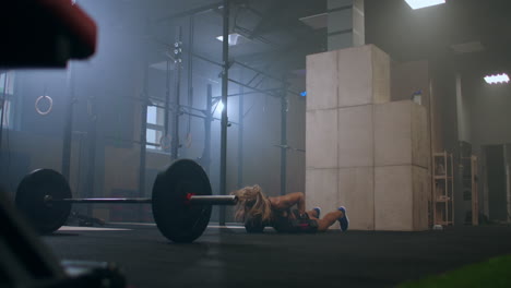 atleta femenina fuerte realizar flexiones con pesas levantando pesas sobre su cabeza después de un salto