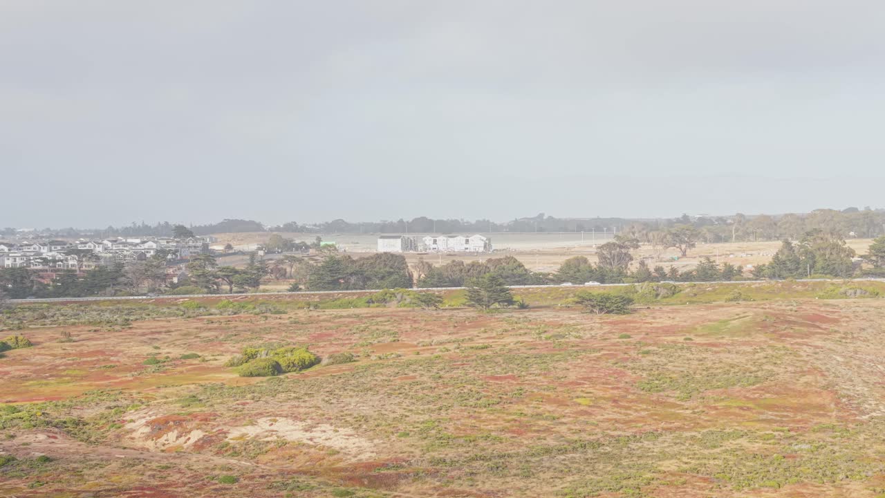 Rolling hills meet coastal sands as Highway 1 winds faintly along the edge of Marina’s scenic shoreline.