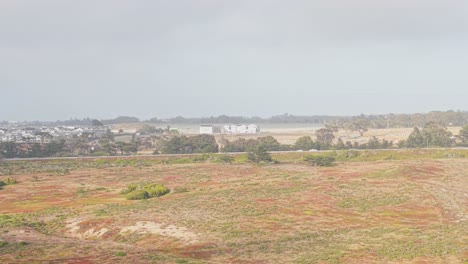 rolling hills meet coastal sands as highway 1 winds faintly along the edge of marina’s scenic shoreline.