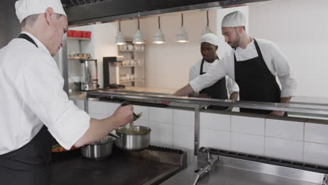 group of diverse male chefs preparing meals in kitchen, slow motion