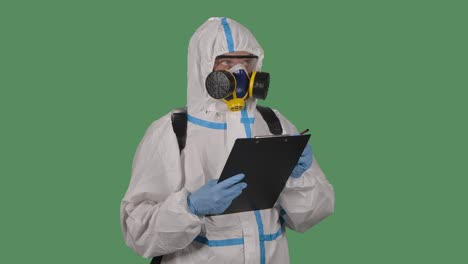 retrato de un hombre con un traje de protección, gafas, guantes y un respirador sostiene una carpeta y marca lugares potencialmente peligrosos. pantalla verde, llave de croma. cámara lenta. primer plano