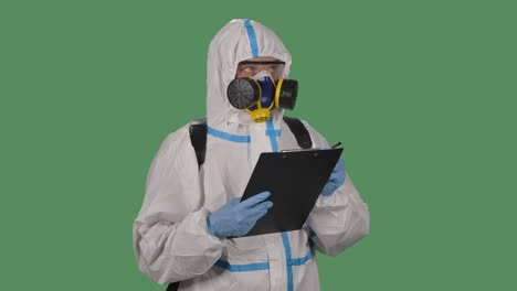 portrait of a man in a protective suit, goggles, gloves and a respirator holds a folder and marks potentially dangerous places . green screen, chroma key. slow motion. close up