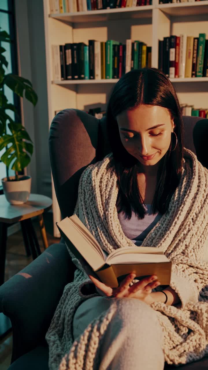 Scène de lecture confortable avec une femme sous une couverture tricotée, filmée en plongée