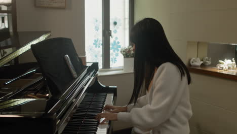 asian girl practicing piano at home